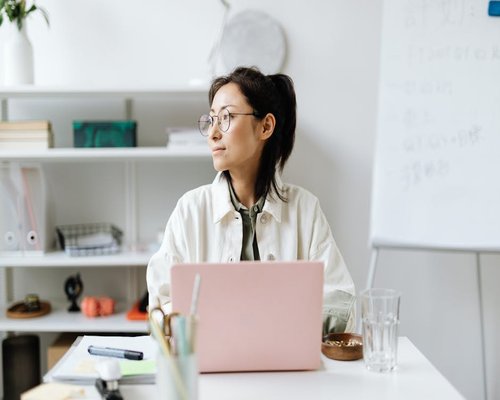 Woman wearing glasses working on laptop in modern office